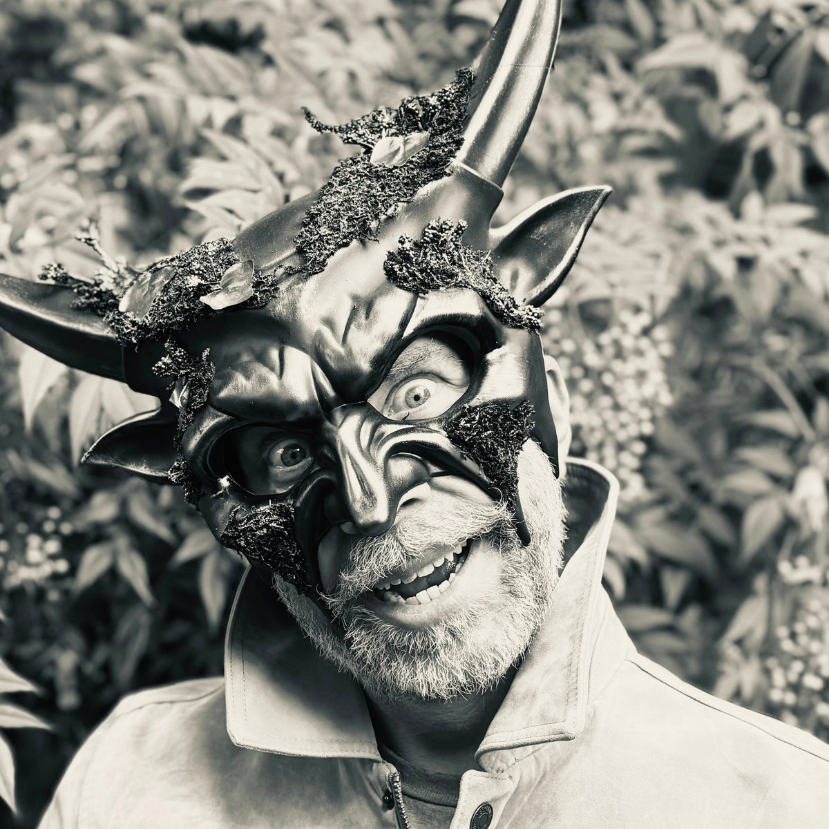 Person wearing a detailed mask with horns and fur in a natural setting